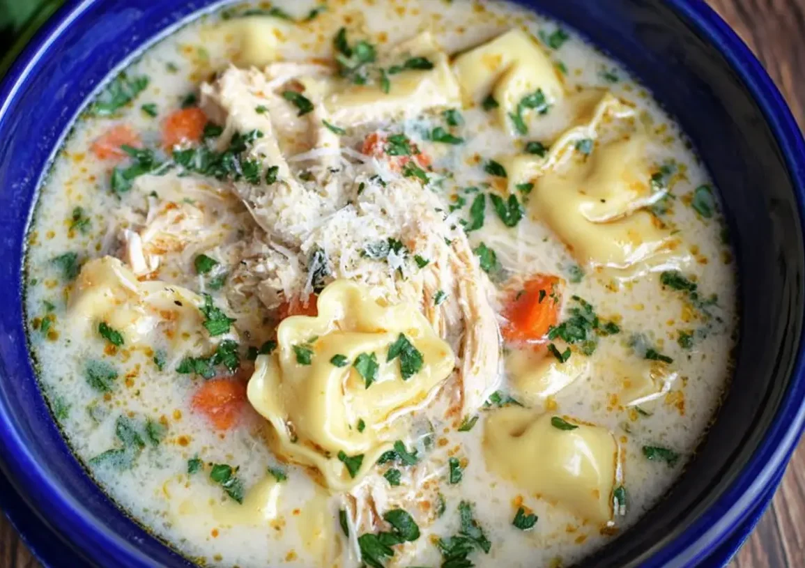 Creamy chicken tortellini soup, perfect for using up rotisserie chicken in leftover soup recipes, garnished with fresh parsley and Parmesan on a rustic wooden background.